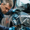 Garage owner assessing damage to a customer’s vehicle inside an auto repair shop, highlighting the importance of proper business insurance coverage.