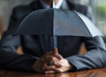 A businessman in professional attire holding an umbrella, symbolizing protection and understanding of garage insurance quotes.