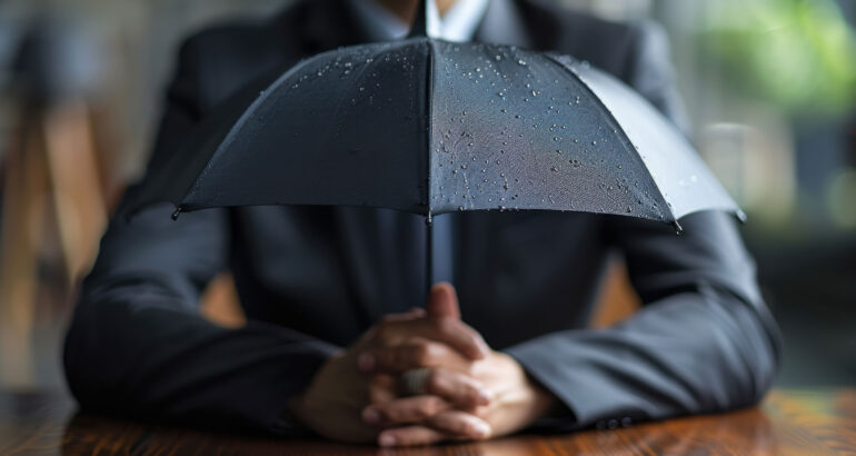 A businessman in professional attire holding an umbrella, symbolizing protection and understanding of garage insurance quotes.